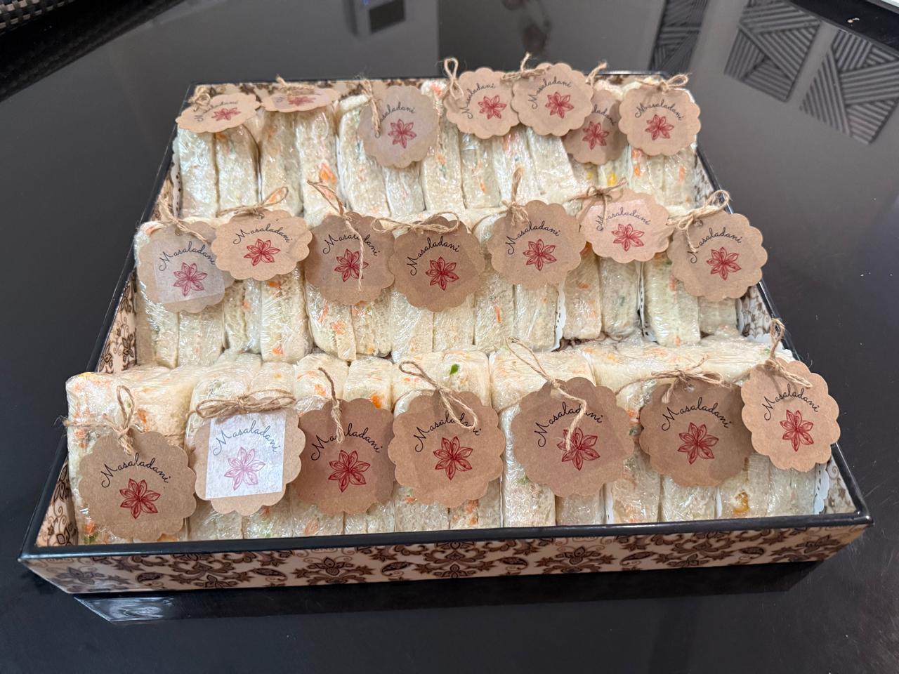 Tray of wrapped sandwiches, each tied with a kraft Masaladani tag