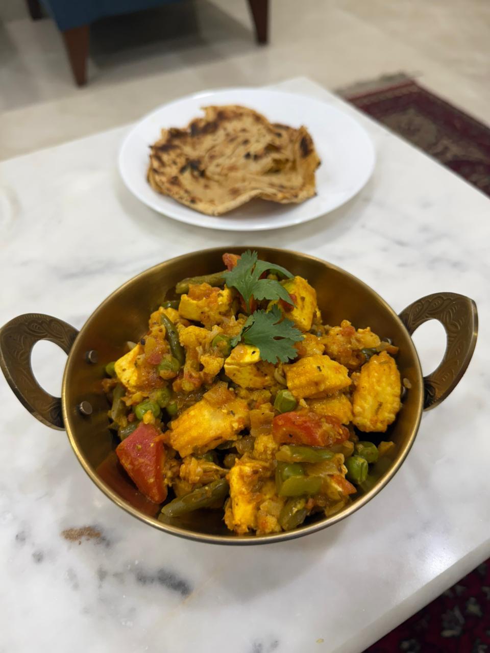 Kadhai paneer with a laccha paratha on a marble table