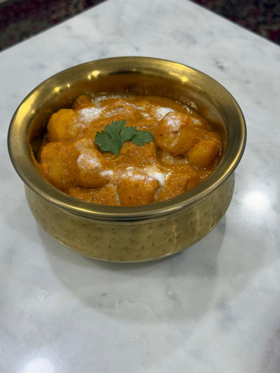 Dum aloo in a brass handi, finished with cream and coriander