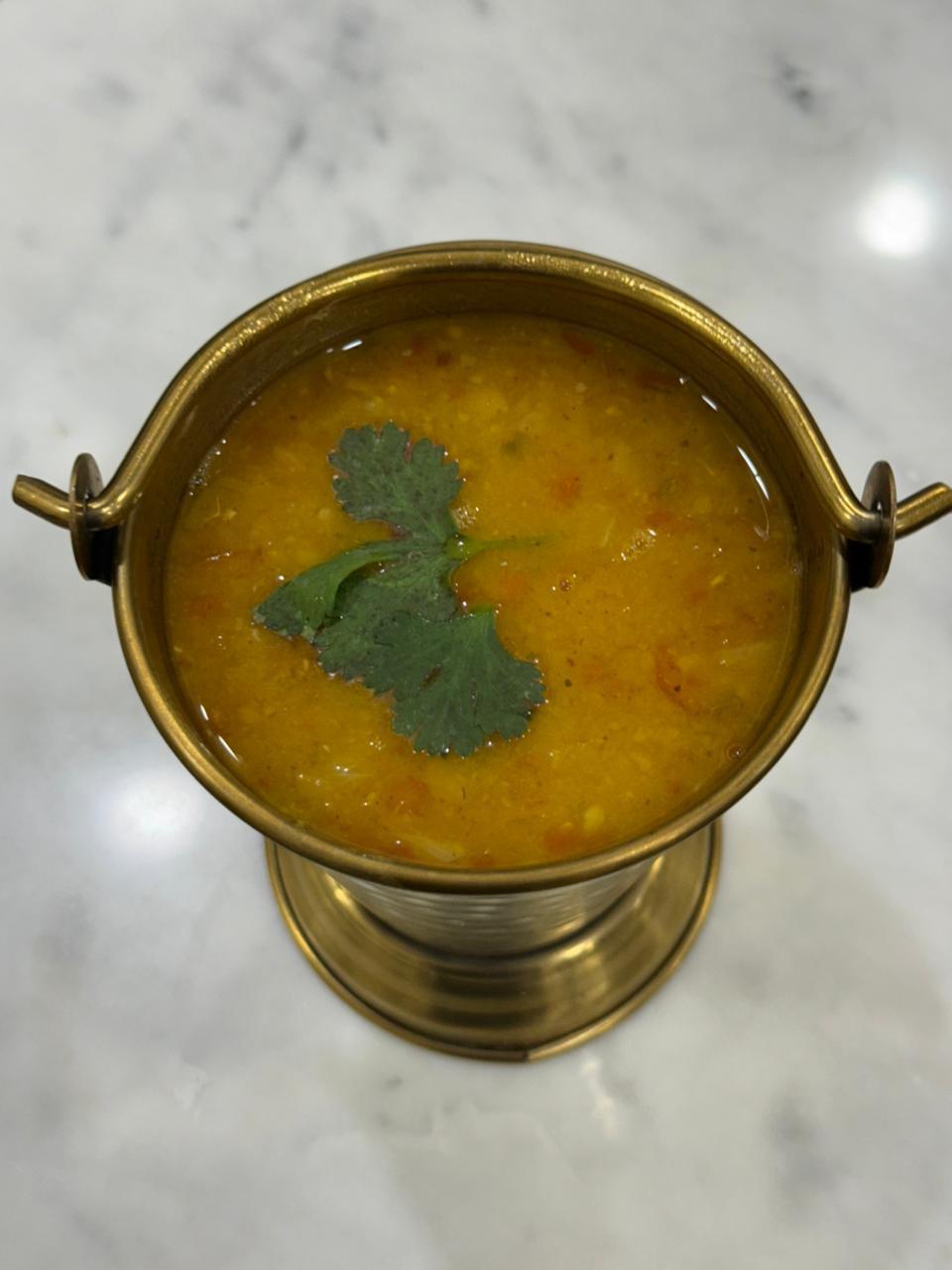 Dal fry in a brass bucket, seen from above with fresh coriander