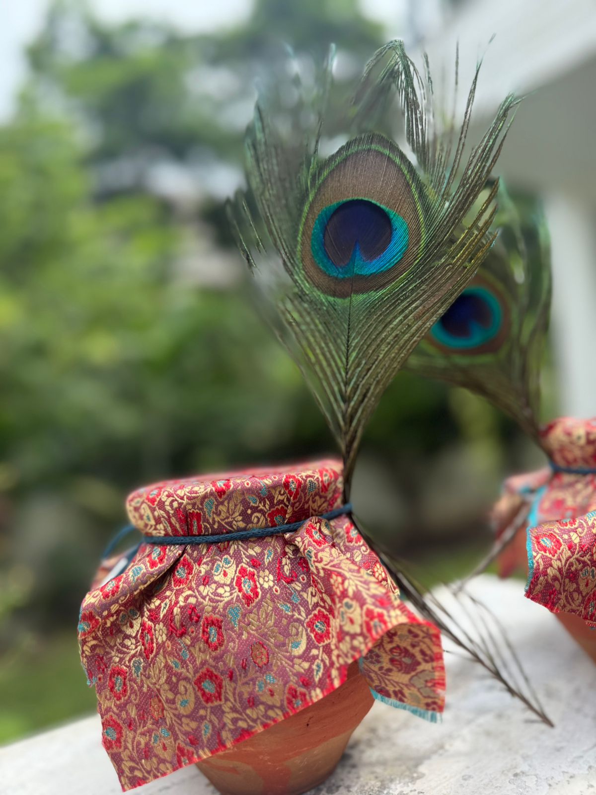 Terracotta matki of makhana kheer sealed with red and gold brocade, a peacock feather tucked into the tie